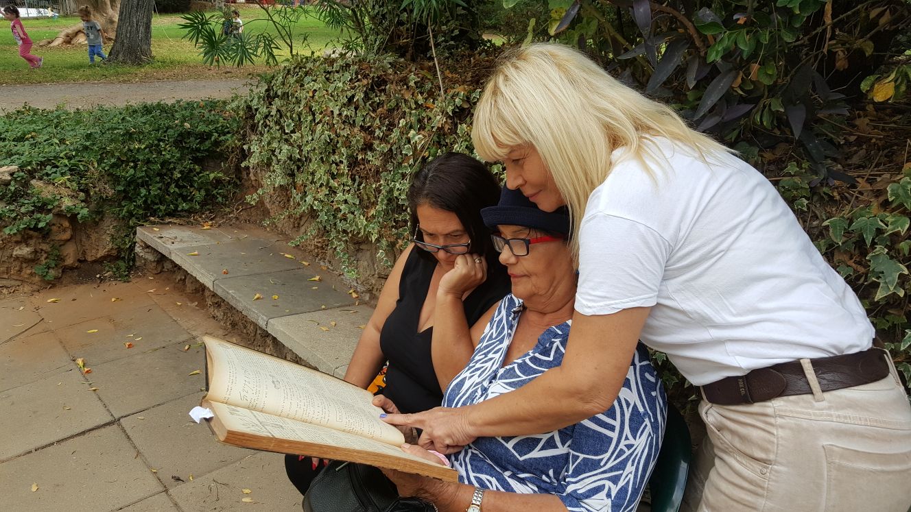 שושנה (עומדת), אחותה מזל ואחייניתם קוראות את ההספד שנכתב על יצחק ז"ל בעלון מעברות