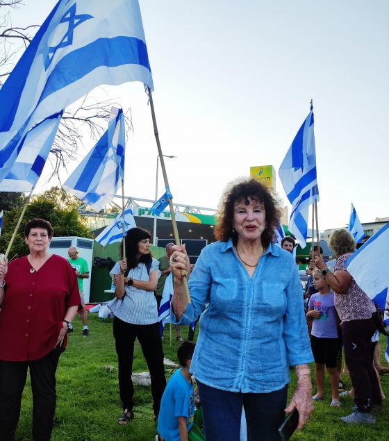 אילנה גבעוני בת ה-88 מפגינה בצומת העוגן עם דגל ישראל