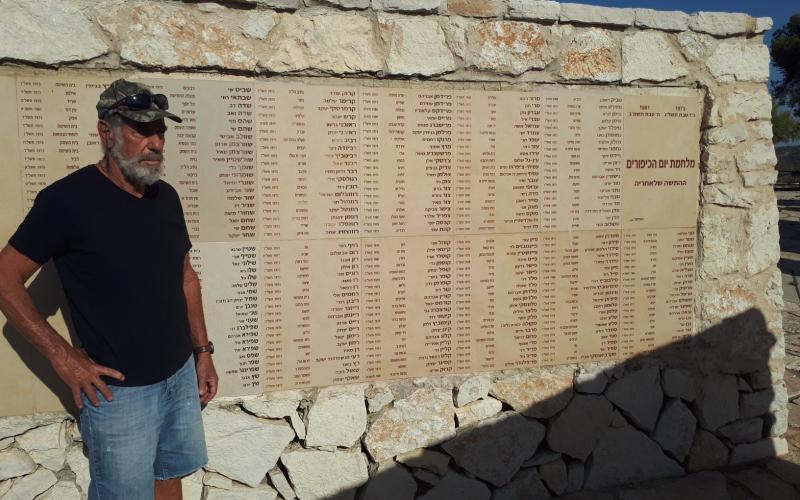 אמנון ישראלי מעין השופט שלחם בחזית הדרום במלחמת יום כיפור ליד הקיר באנדרטה בו חקוקים שמות הנופלים